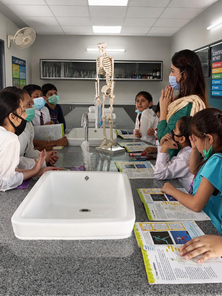 Students around a laboratory bench at a Vantage chapter, working from their textbooks with a teacher and a model skeleton.